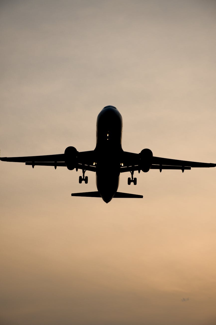 Dramatic silhouette of an airplane flying against a warm sunset sky, capturing the essence of travel and adventure.