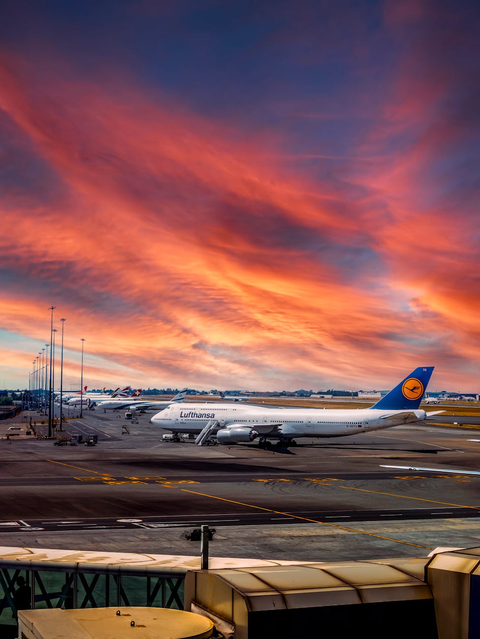 Lufthansa airplane on tarmac at Johannesburg airport during a vibrant sunset, showcasing aviation beauty.