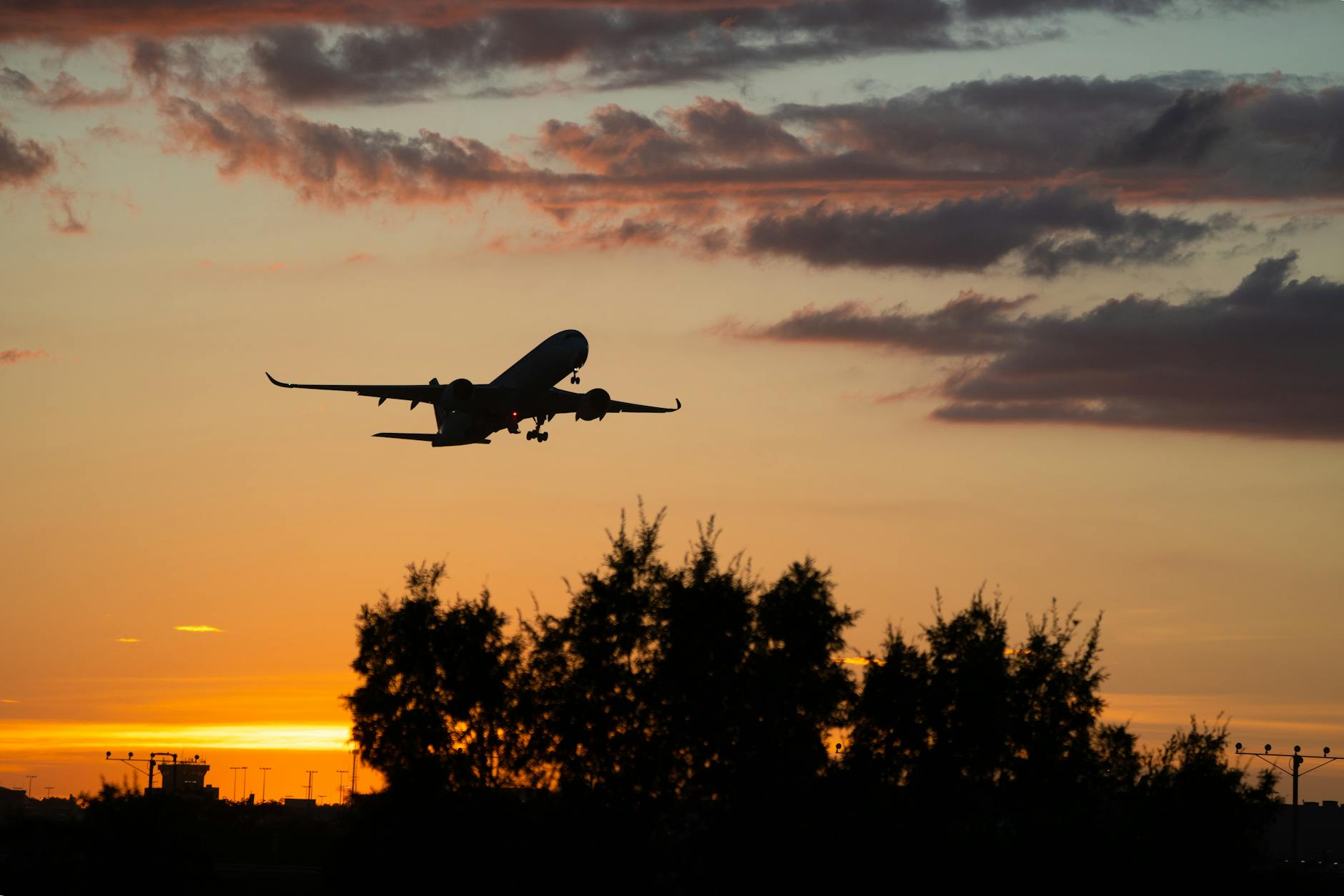 Silhouette of an airplane in flight against a vibrant sunset sky.