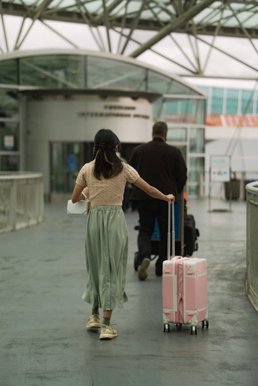 A man and woman with luggage entering an airport terminal, symbolizing travel and exploration.