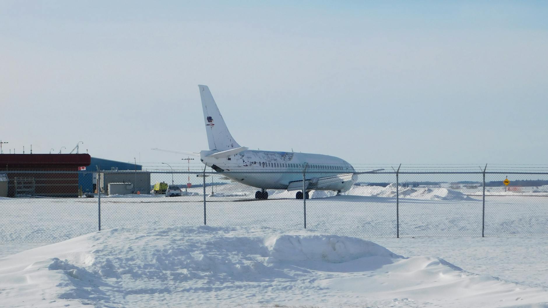 Airplane parked on a snowy runway at an airport, captured in winter conditions.