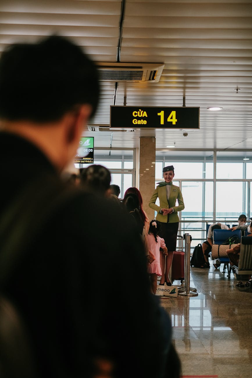 Flight attendant at airport gate 14, Vietnam, offering guidance to passengers indoors.