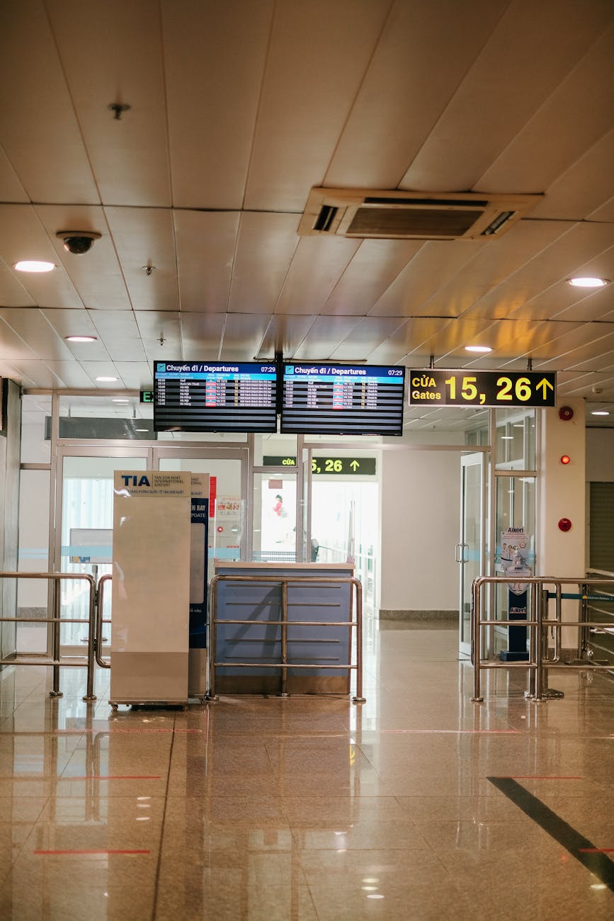 Quiet airport departure gate with digital signage and bright lighting.