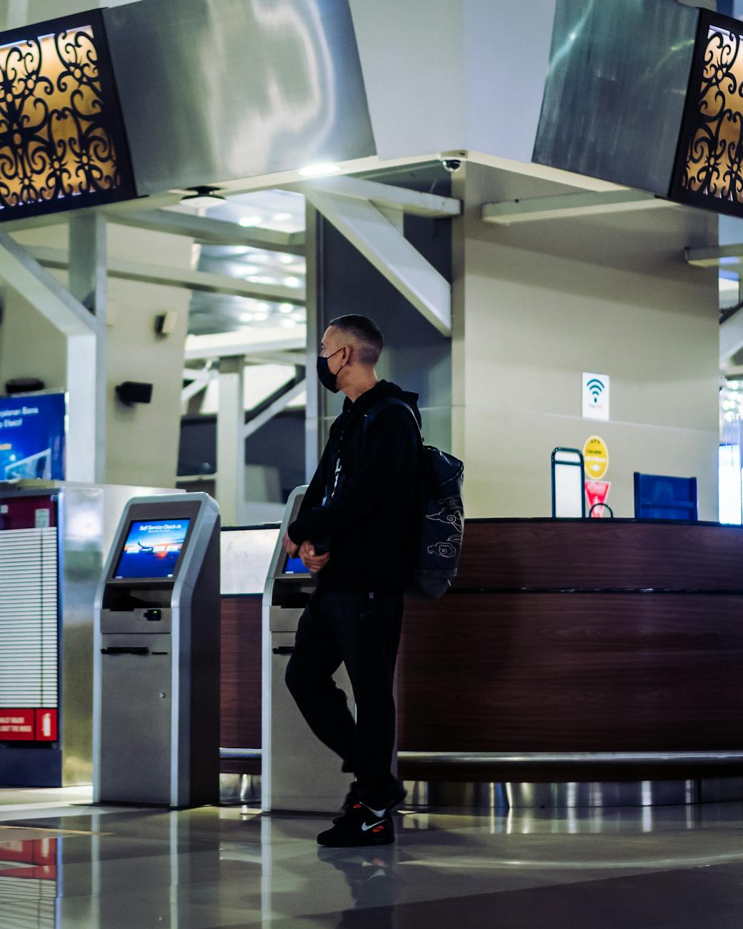 A man wearing a mask at an airport check-in counter during the pandemic.