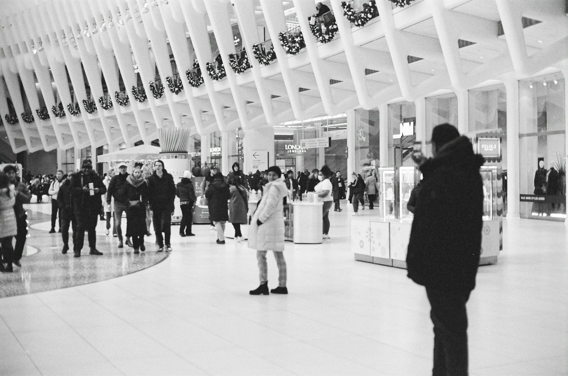 Black and white photo of people walking inside an urban New York shopping mall.