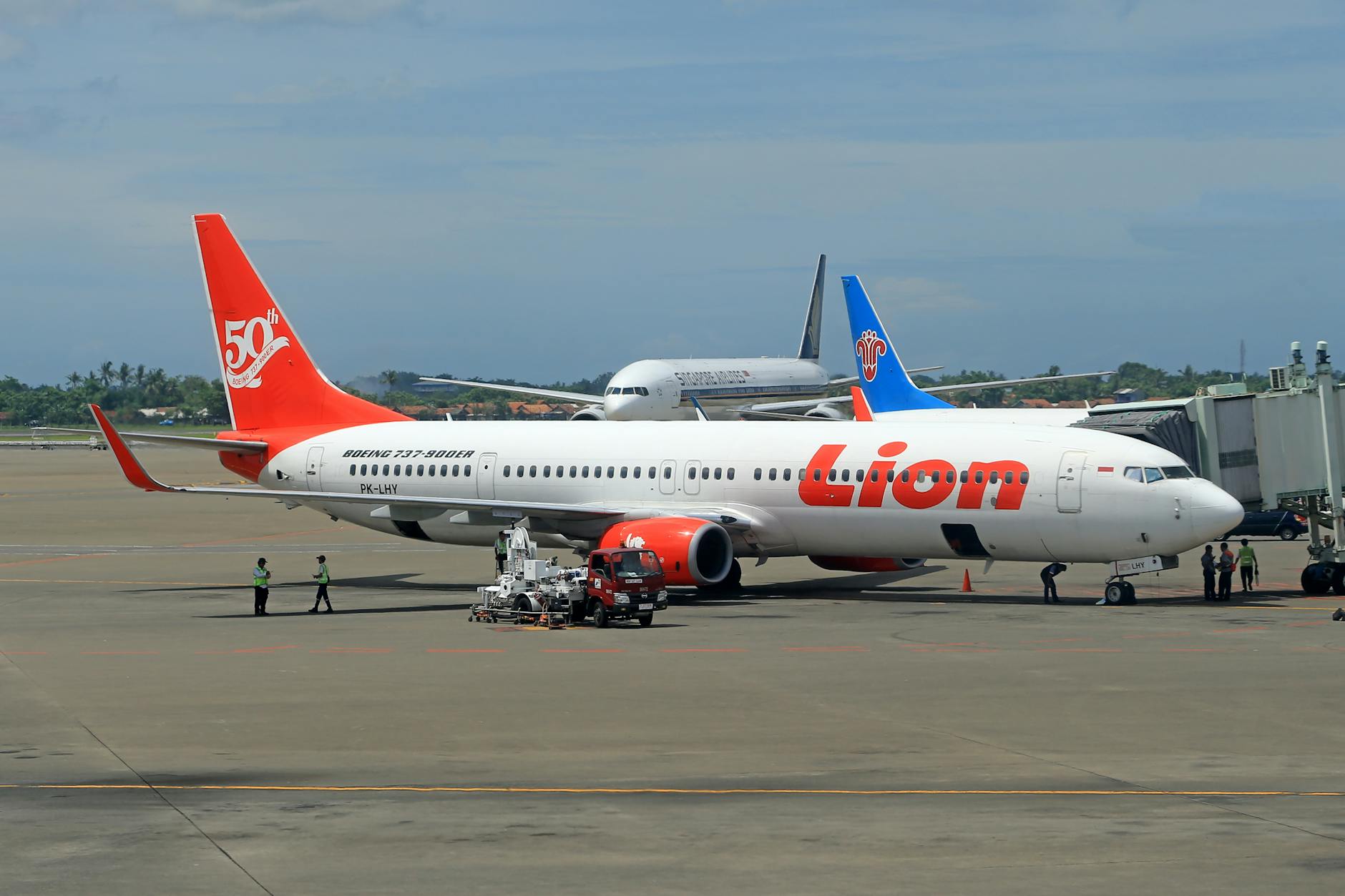 Lion Air Boeing 737 on tarmac with ground crew at an airport.