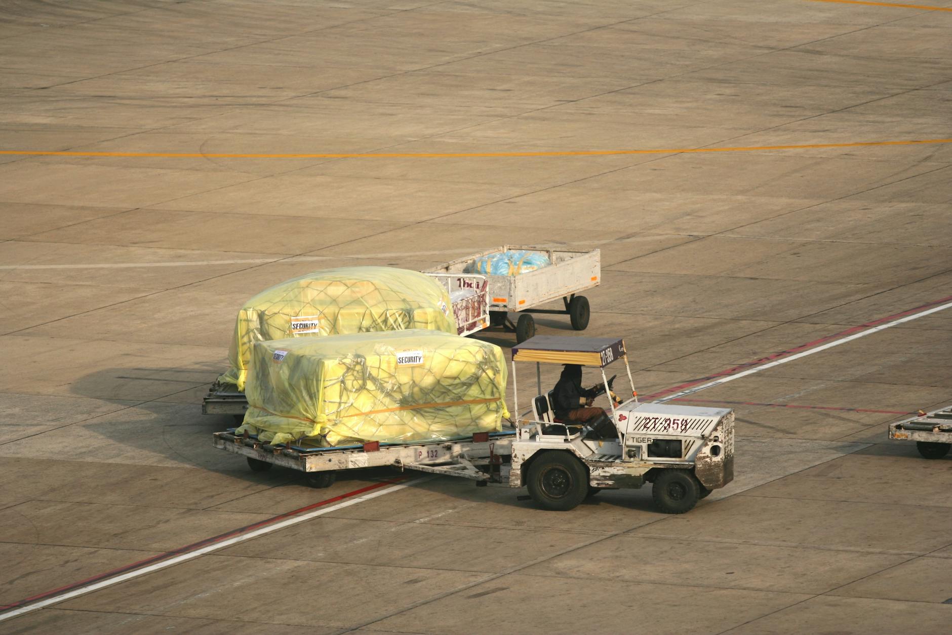 Cargo being handled on the tarmac at Bangkok Airport. Seen from above, this includes trailers and ground staff.