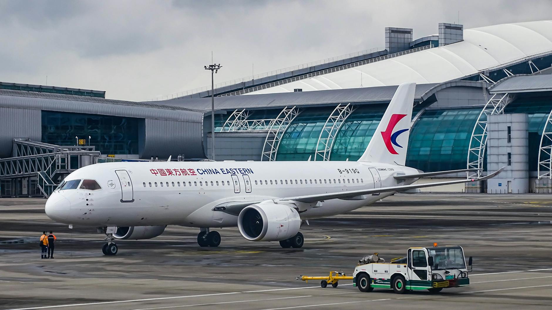 China Eastern Airlines Airbus parked at a modern airport terminal on a cloudy day, ready for departure.