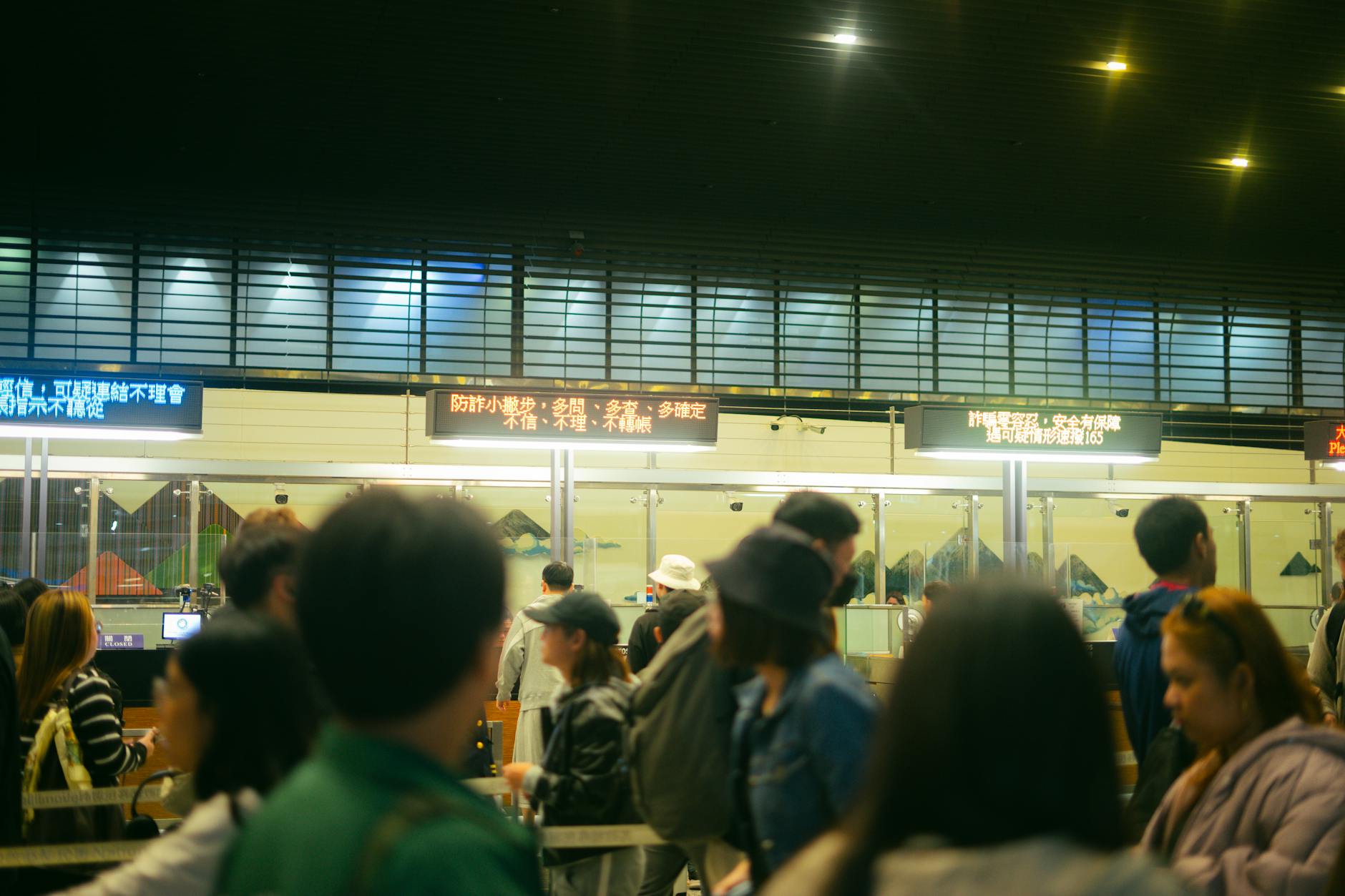 Crowded airport check-in area with people queueing and visible flight information signs.