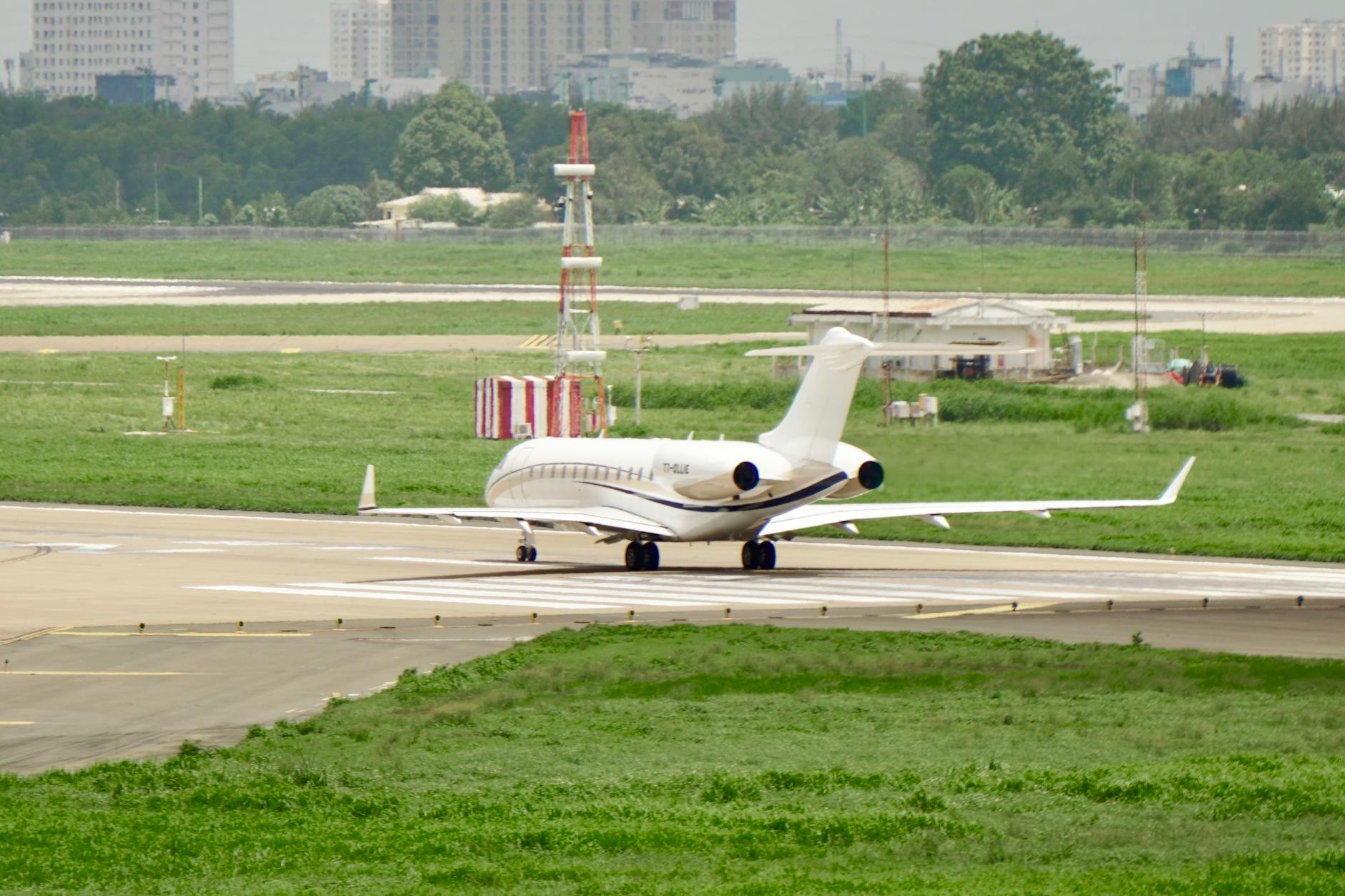 A sleek private jet taxiing on a runway at an international airport, with city skyline in the background.