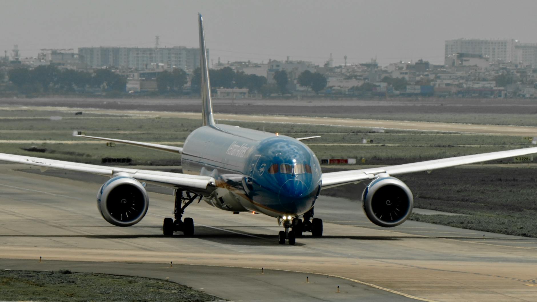 Front view of a large commercial airplane taxiing on a runway at an airport.