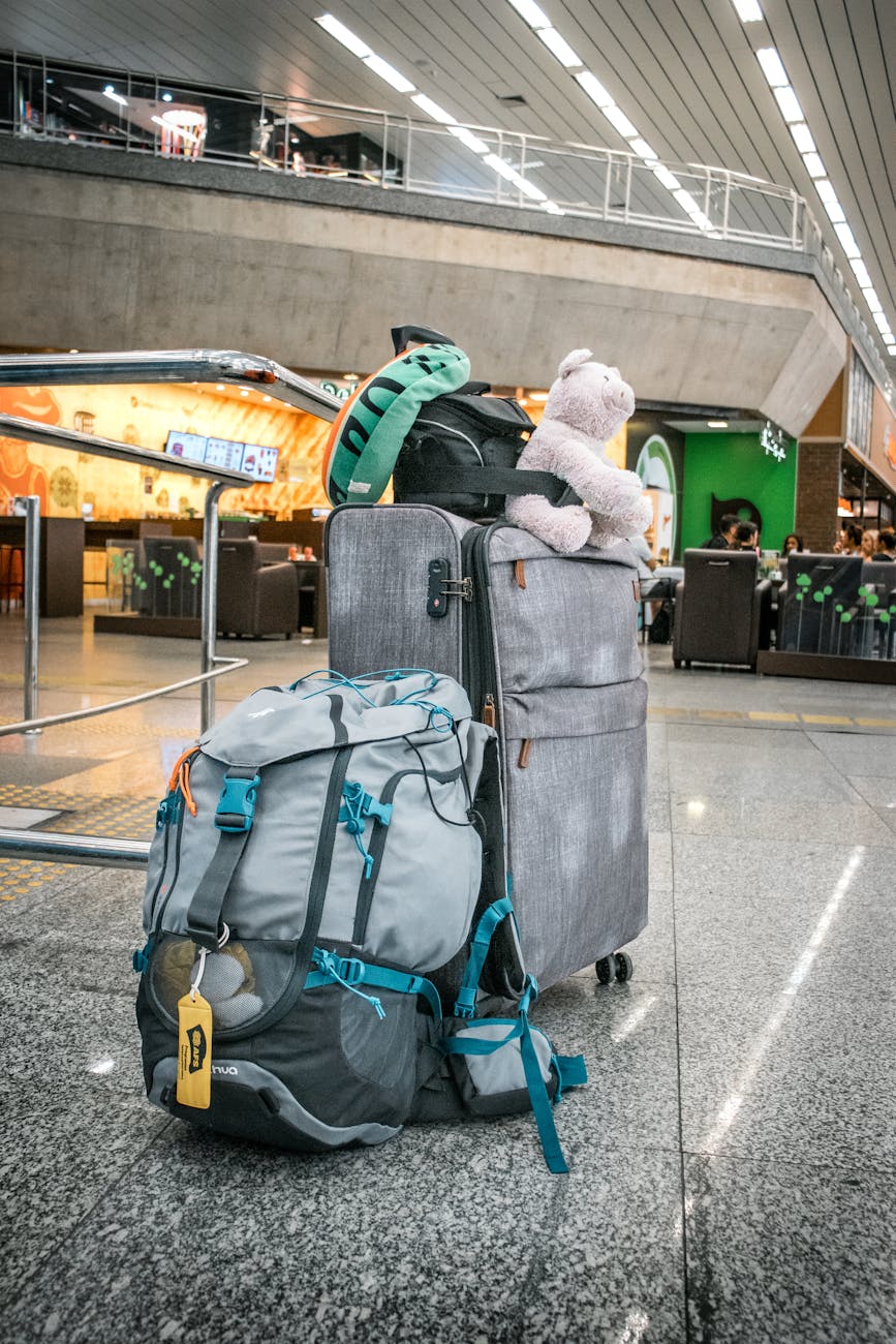 Travel bags with a teddy bear are ready for departure at a modern airport terminal.