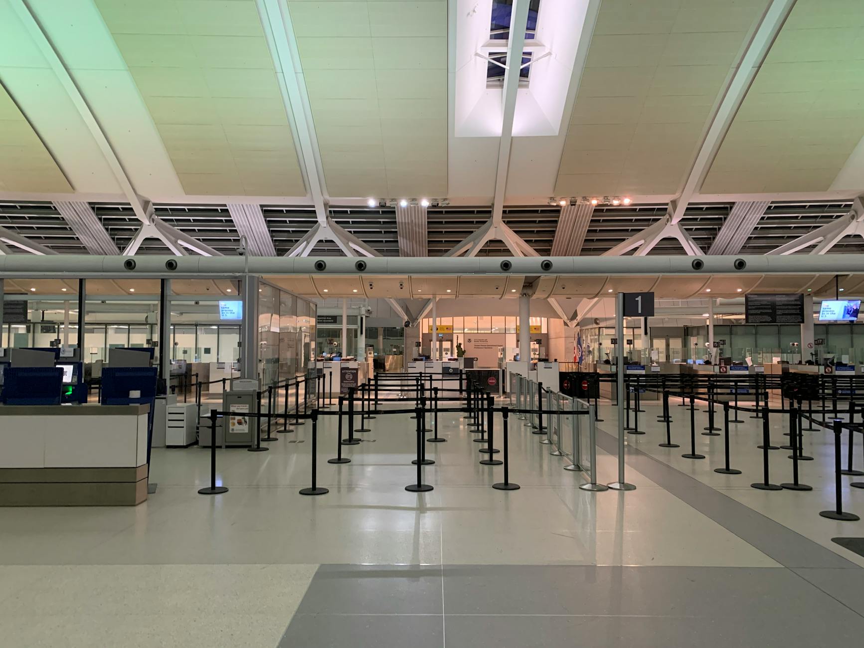 Empty check-in area of a modern airport with sleek design and organized layout.