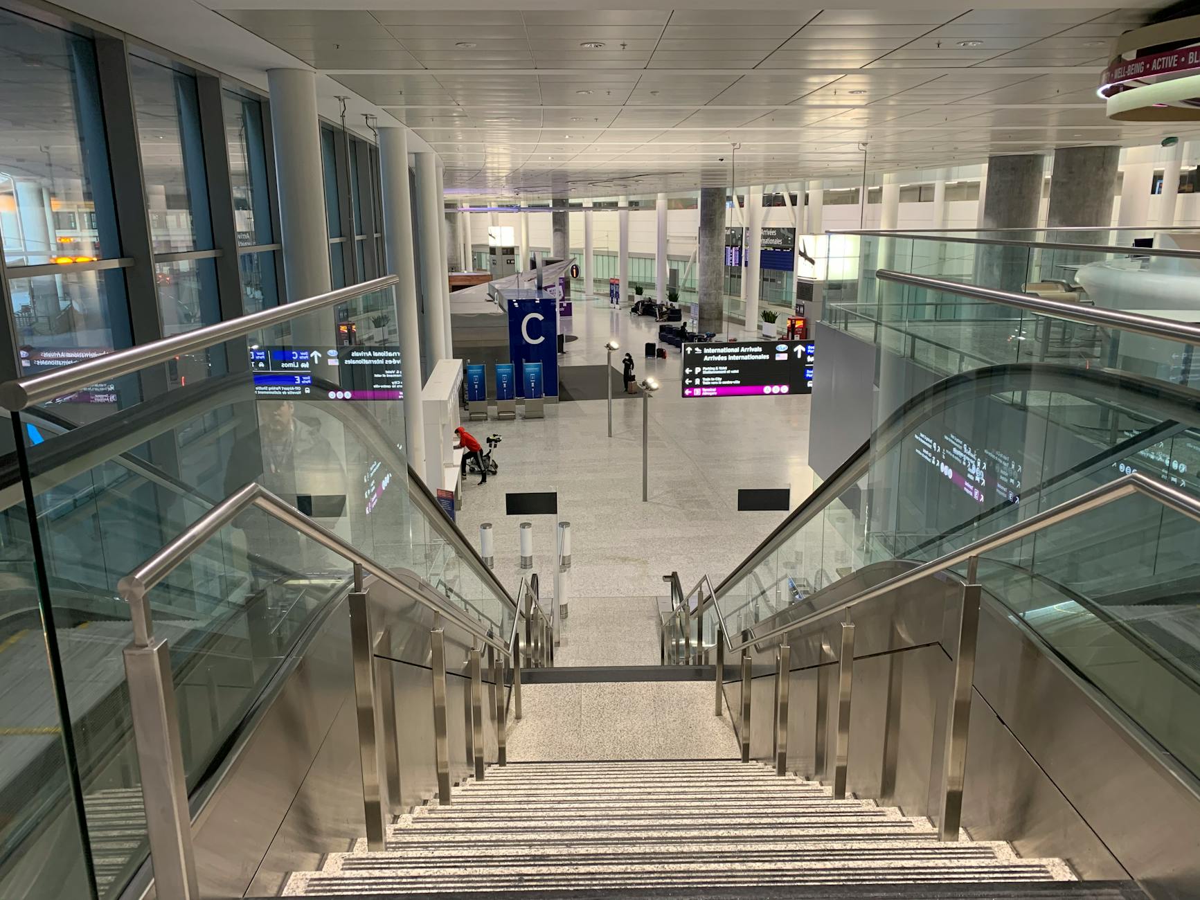 Spacious airport terminal featuring a modern staircase and glass railings enhancing architectural design.
