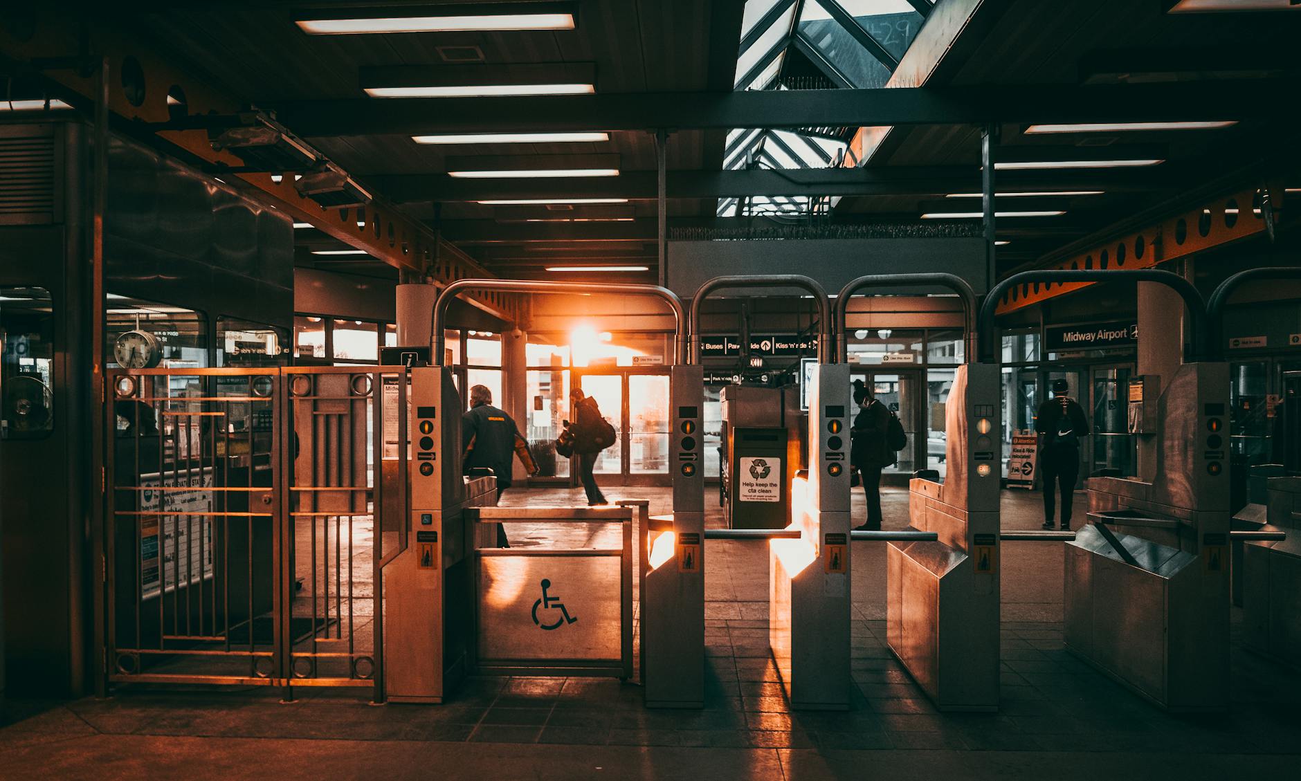 Commuters at an urban train station with warm sunlight streaming through the gates.