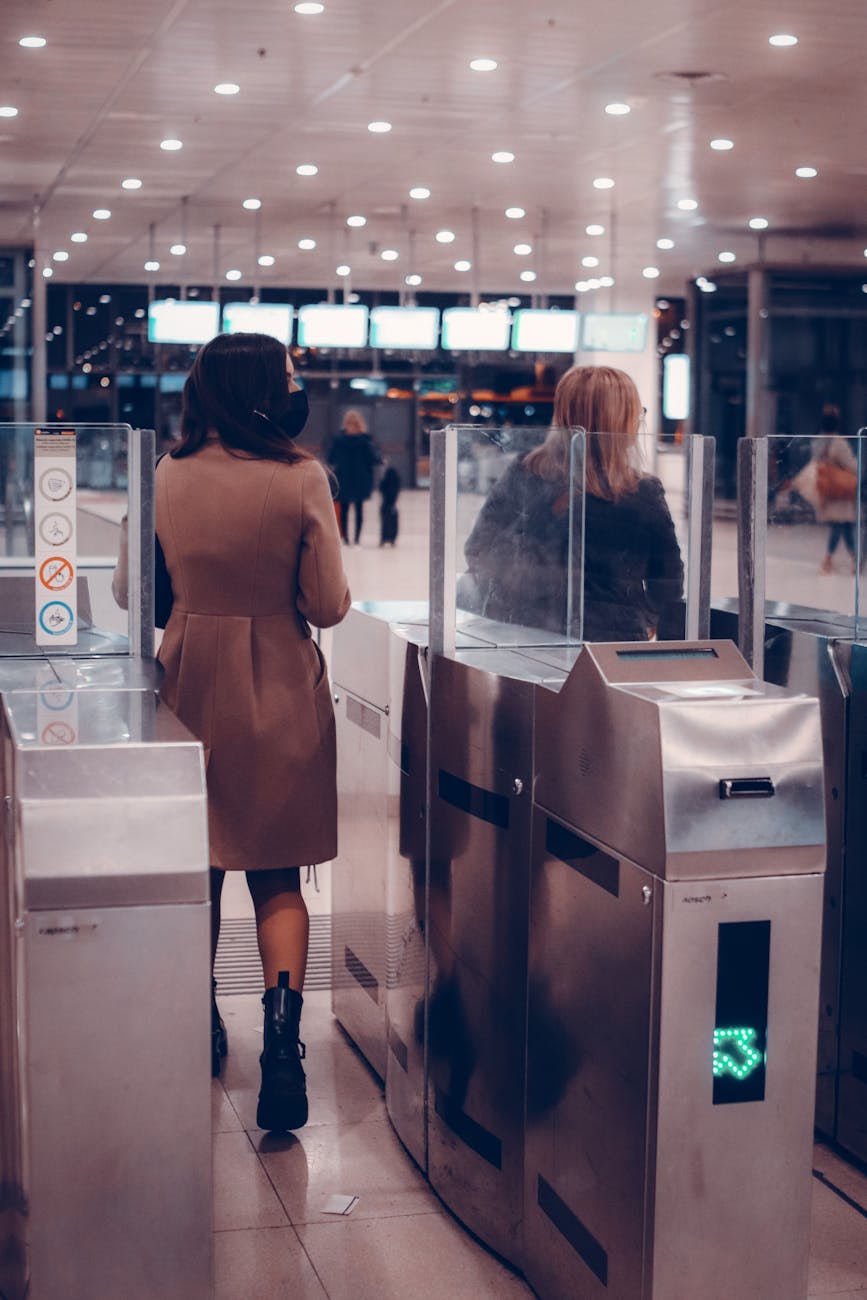 Two women passing through airport security gates, highlighting modern travel.