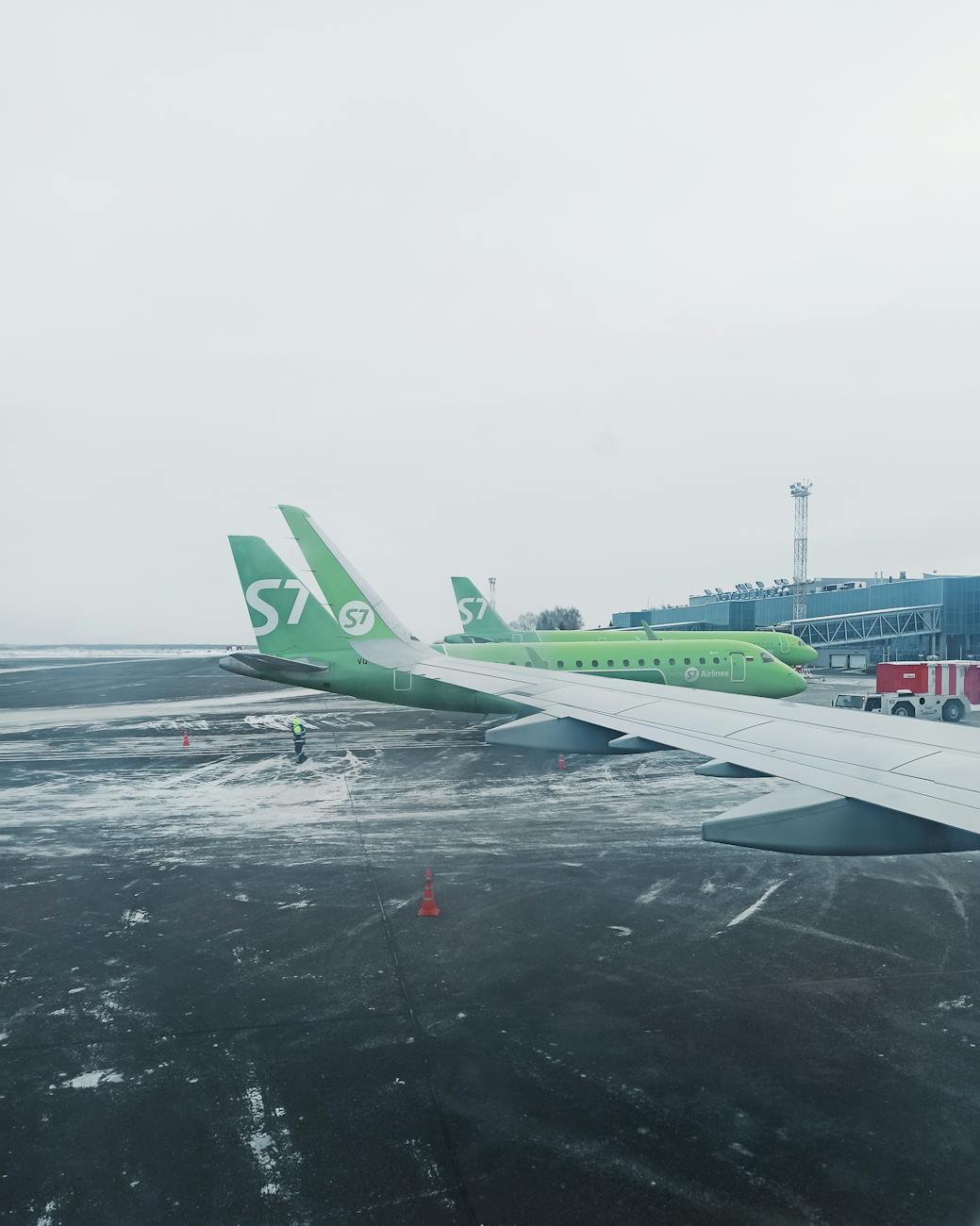 Green commercial airplane parked at snowy airport in Russia, emphasizing aviation travel.