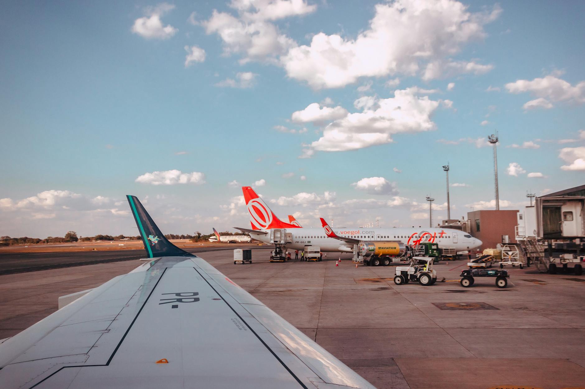 View of airplanes at an airport tarmac, parked under a clear blue sky with clouds.