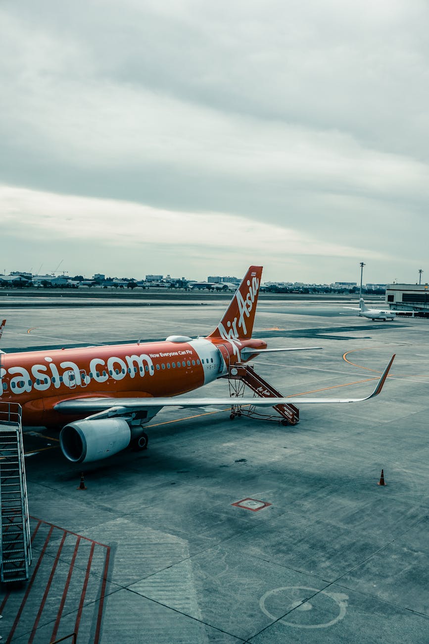 AirAsia airplane parked on runway with cloudy sky at an international airport.