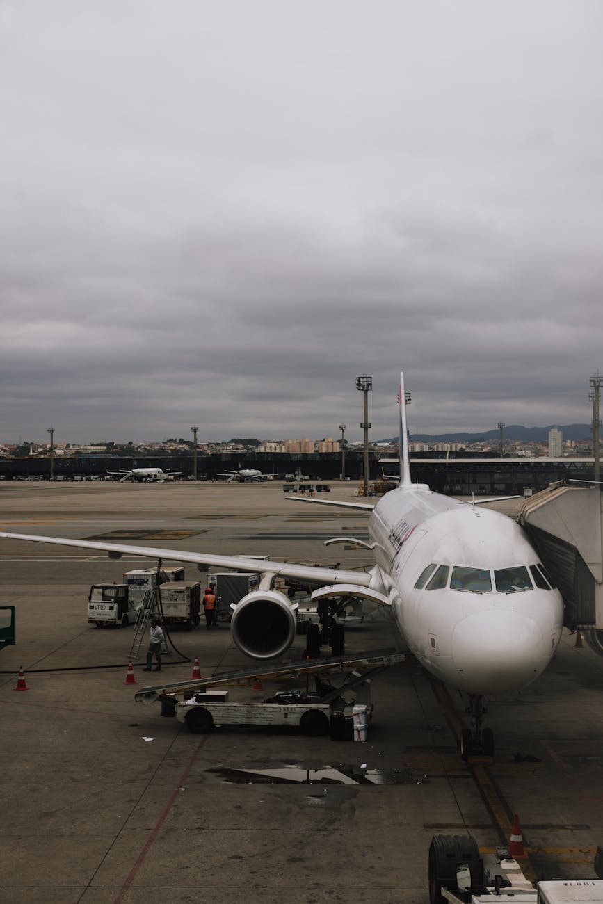A commercial airplane parked at an airport tarmac with cloudy skies, ready for boarding.