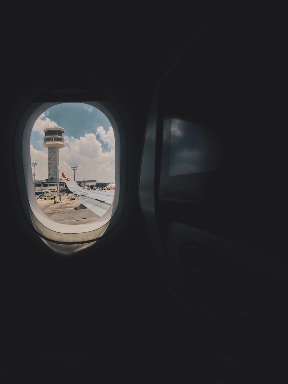 View from airplane window showcasing airport control tower and sky.