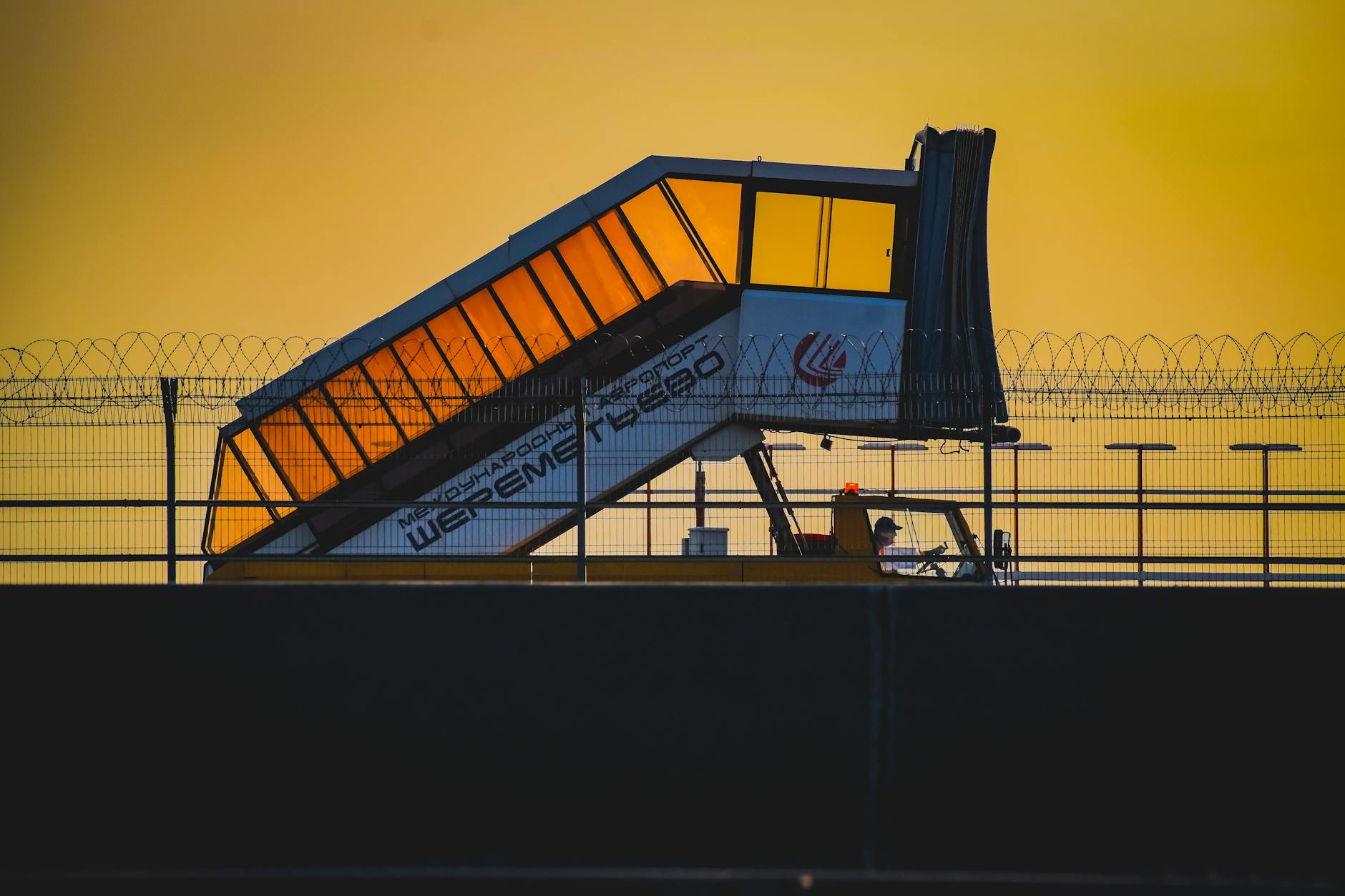 Captivating view of an airport jetway silhouetted against a vibrant sunset sky, creating an intriguing travel scene.