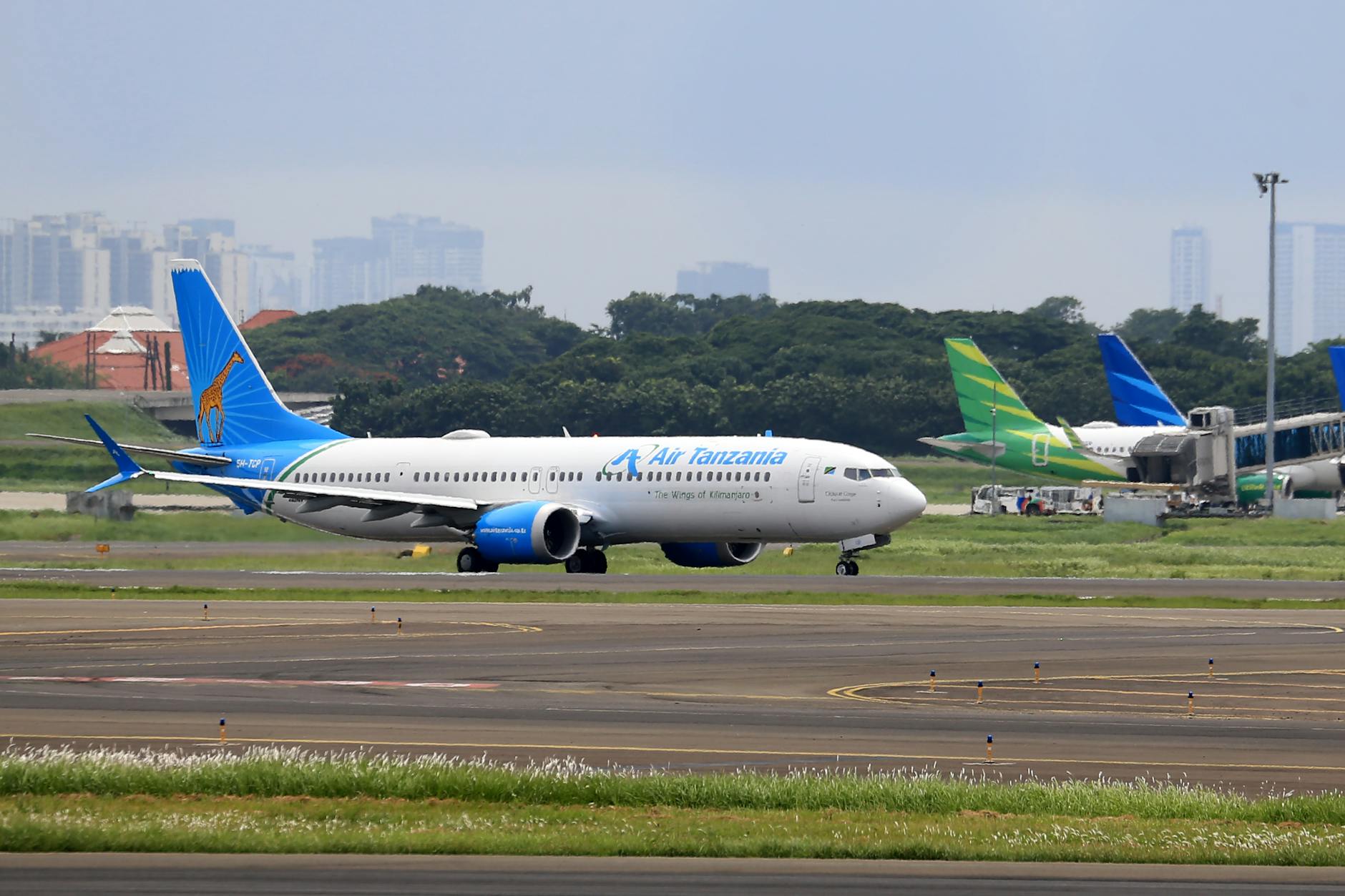Air Tanzania airplane on tarmac at airport with skyline backdrop. Ideal for aviation and travel imagery.