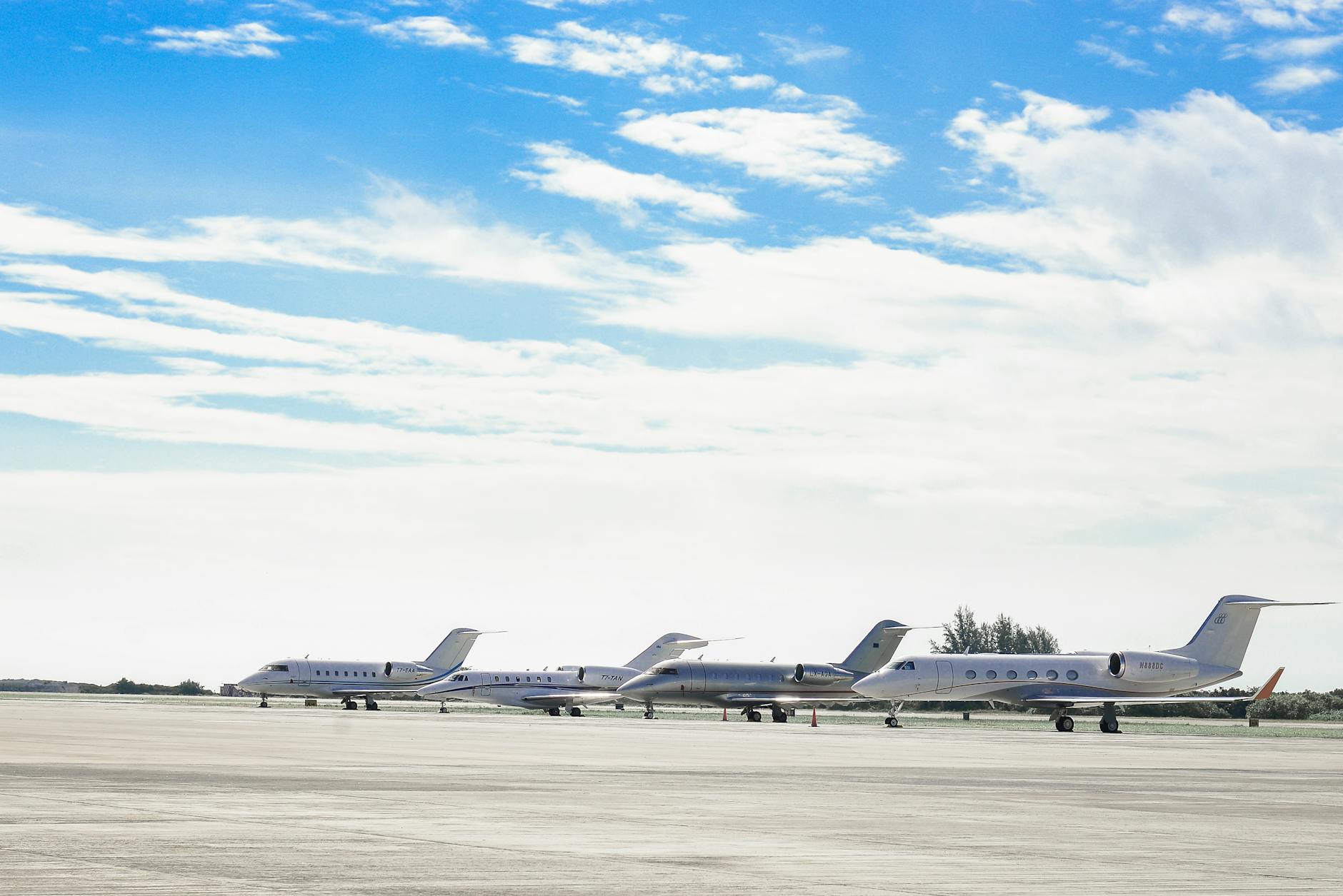 Row of private jets parked on a clear day at an open runway, showcasing aviation and luxury travel.