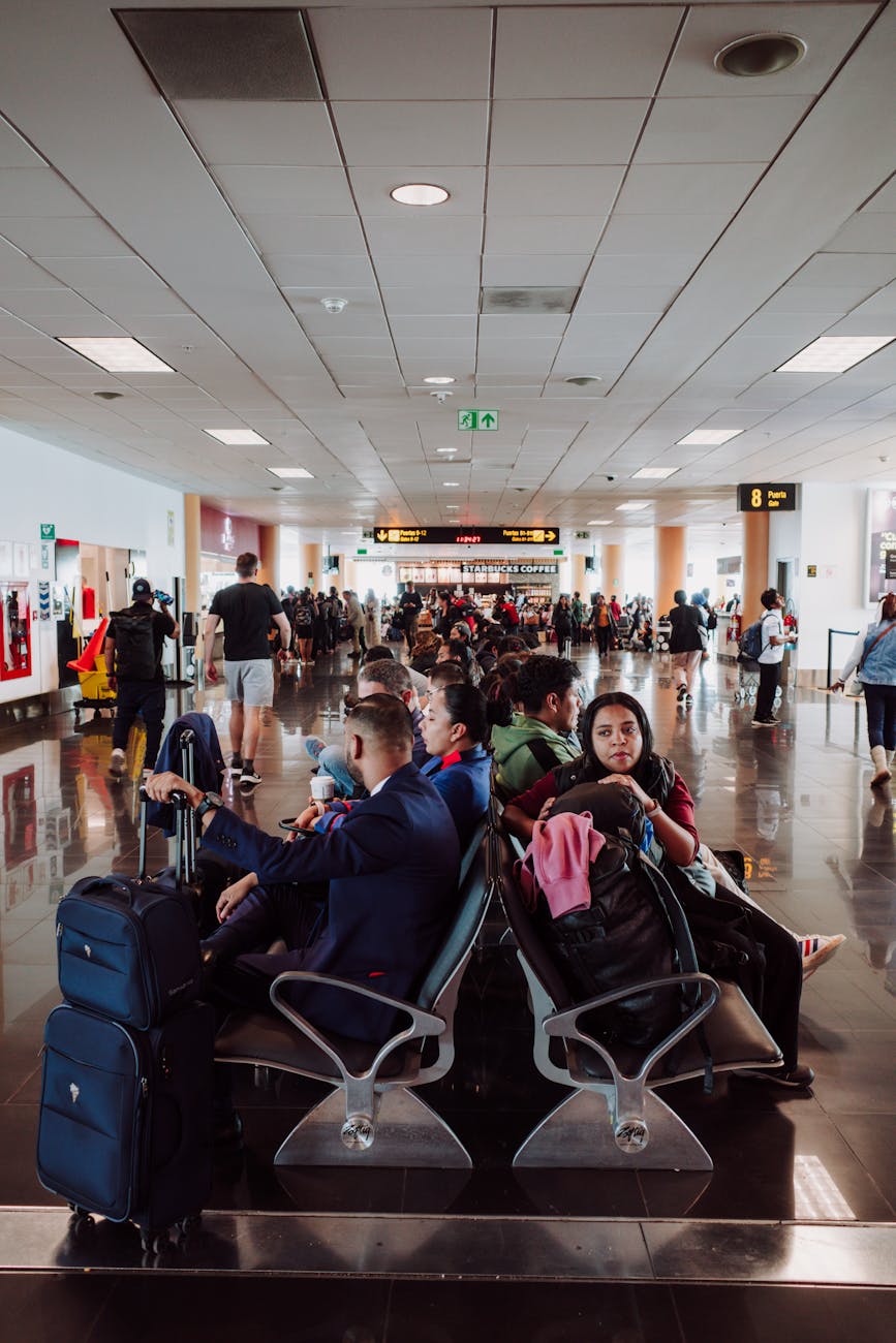 Passengers waiting in a busy airport terminal seating area, with luggage in the modern airport.