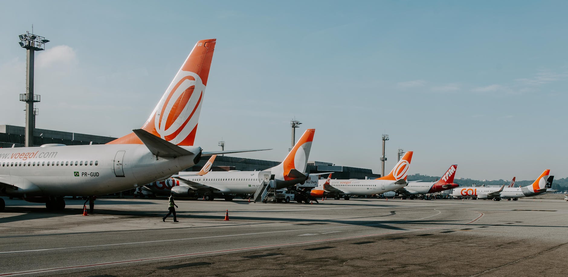 Multiple airplanes on tarmac at a busy airport during daytime, showcasing aviation and travel.