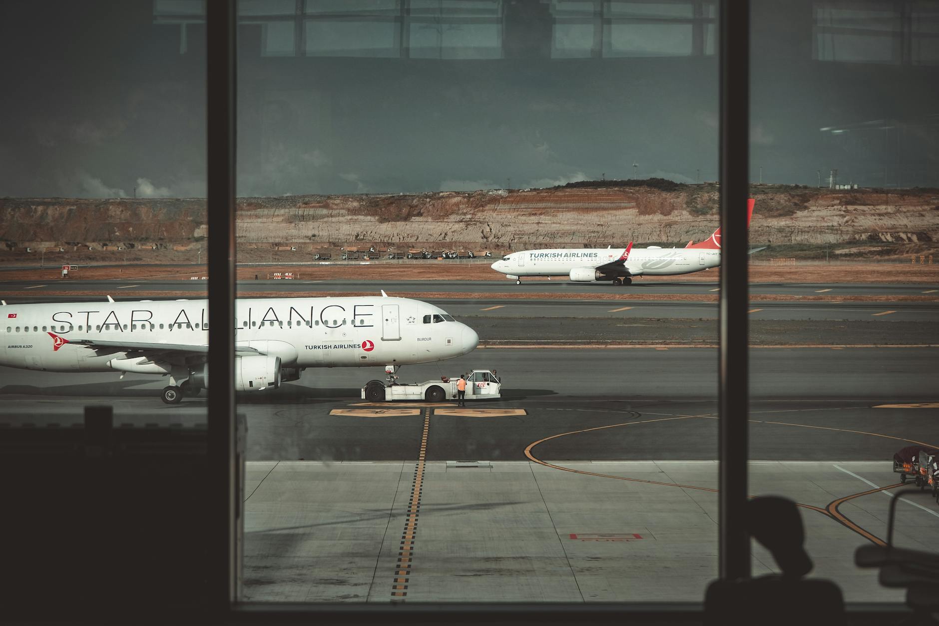 A view through airport windows showing airliners on the runway, creating a travel ambiance.