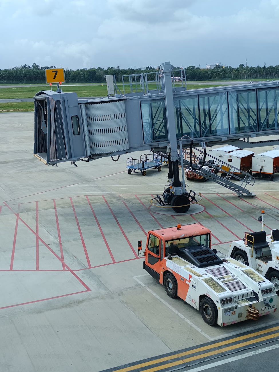 Empty jet bridge and service vehicle on airport runway during day.