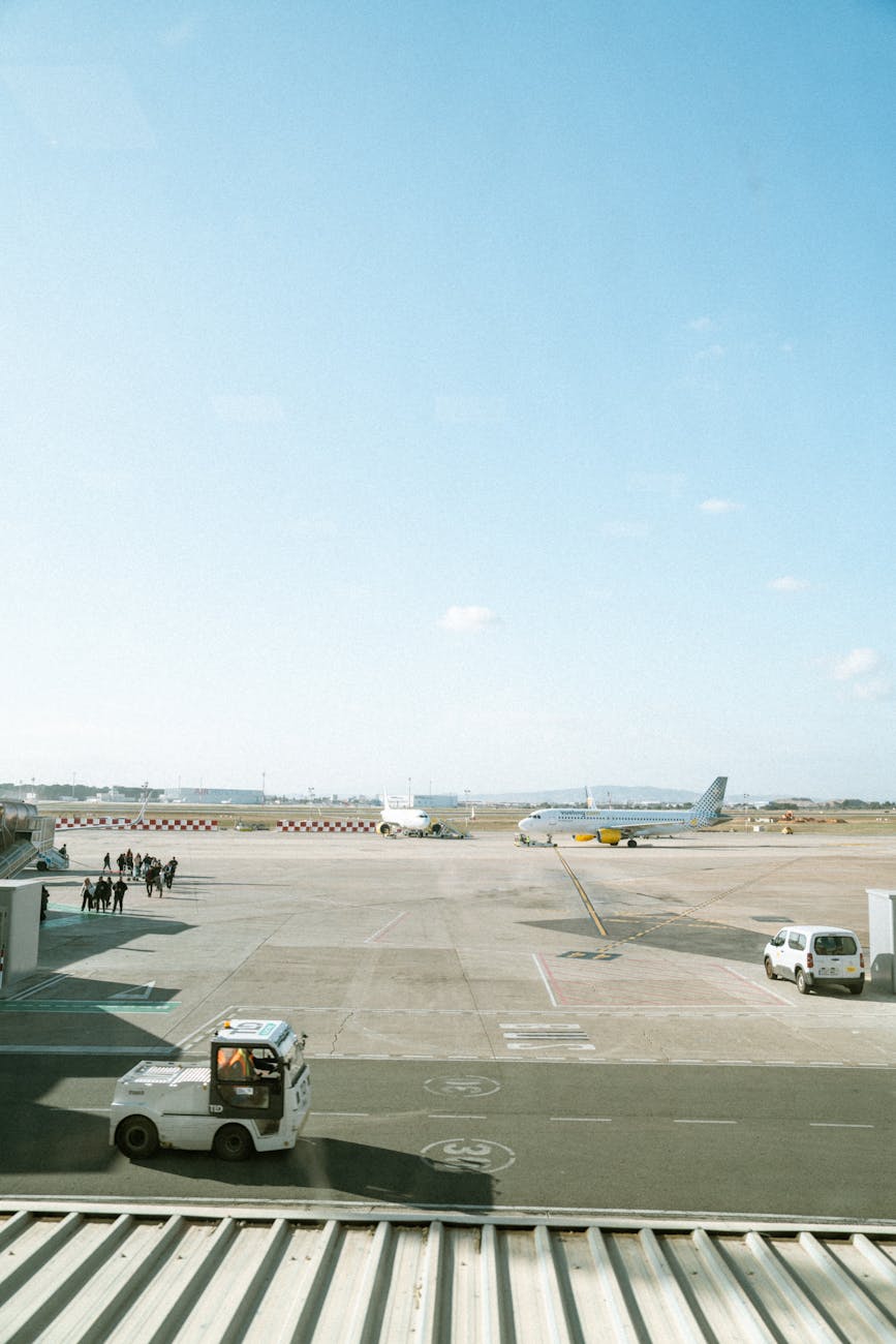 A view of an airport tarmac with an airplane, vehicles, and people moving.