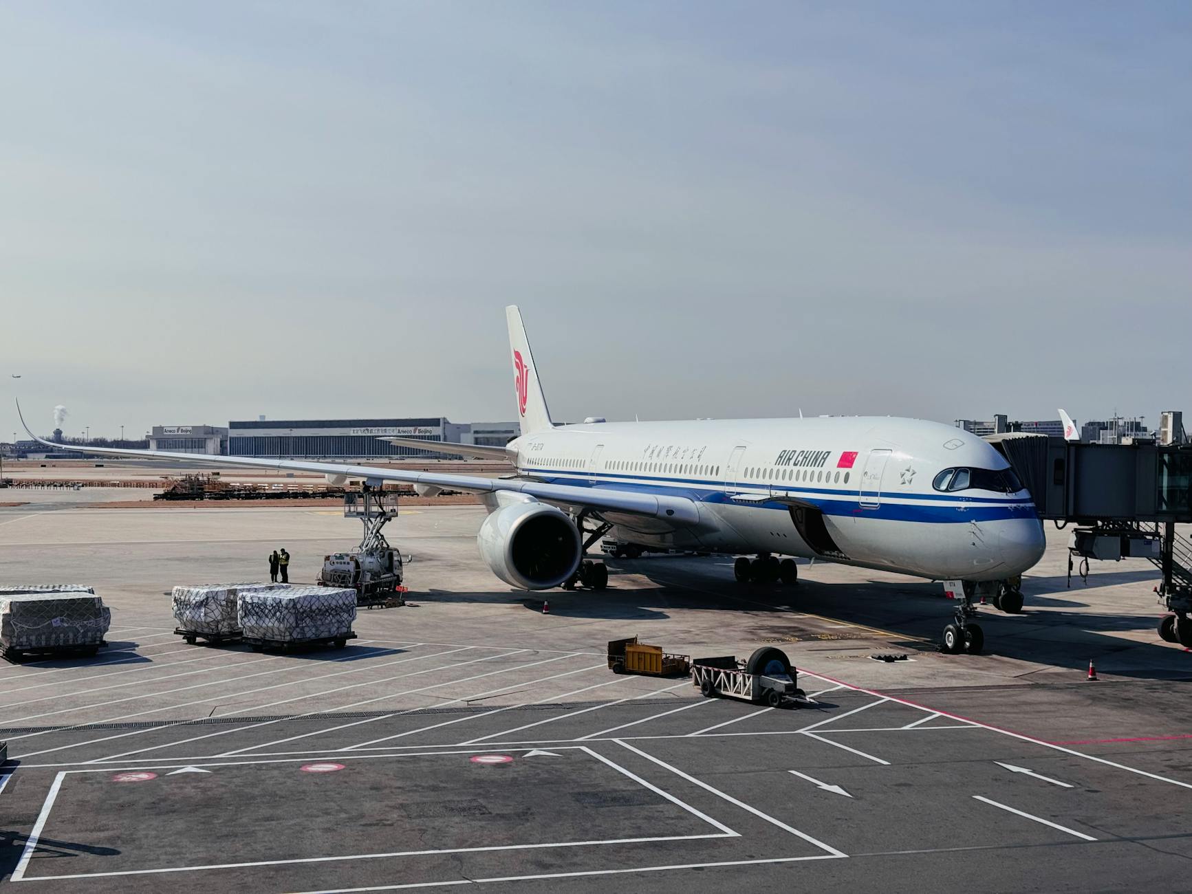 Passenger jet at airport gate with loading services in progress, showcasing modern aviation.
