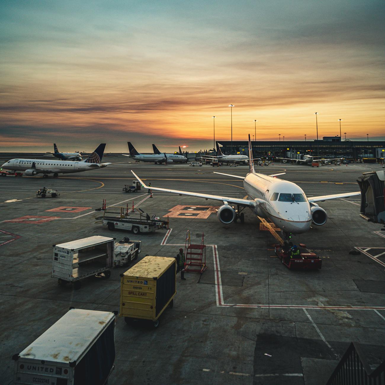Airplanes parked at a busy airport terminal during sunset, showcasing aviation and travel.