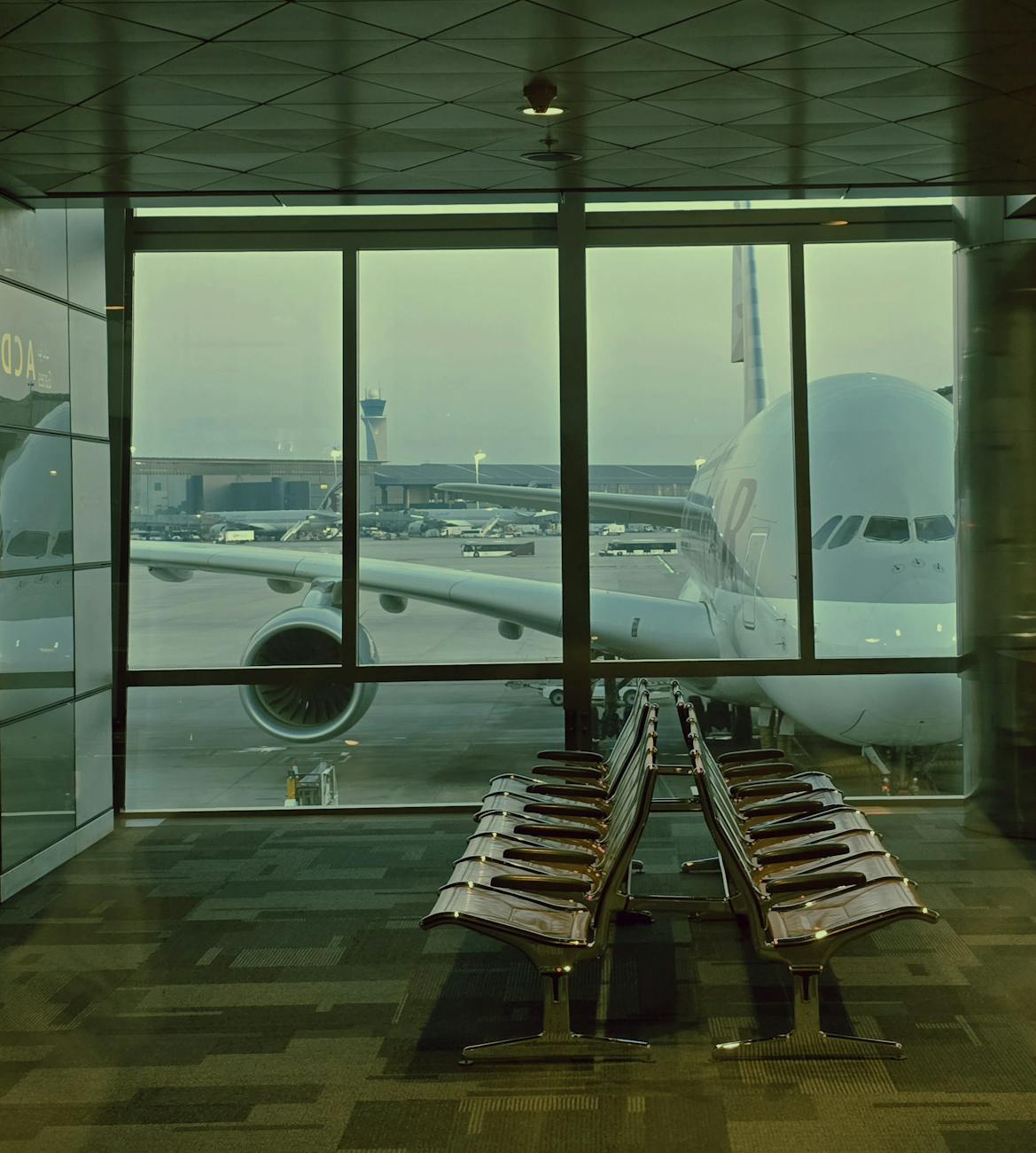 A large airplane is parked outside an airport terminal window at dawn.