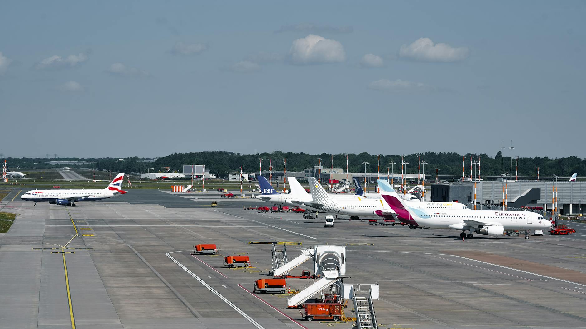 Airplanes on the runway at Hamburg Airport on a clear day, showcasing bustling air travel.