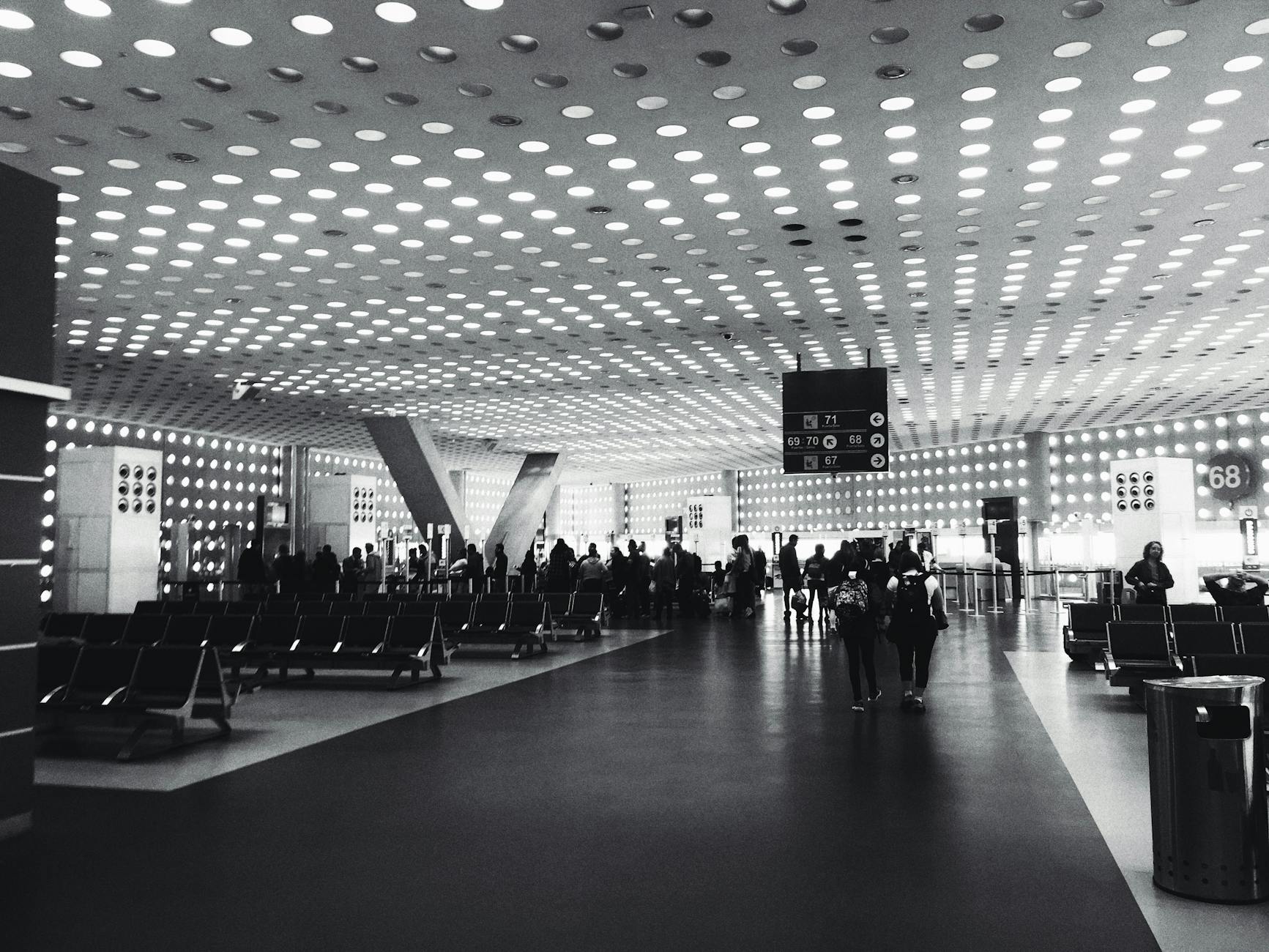 Monochrome image of a busy airport lounge in Mexico City, showcasing modern architecture and travelers.