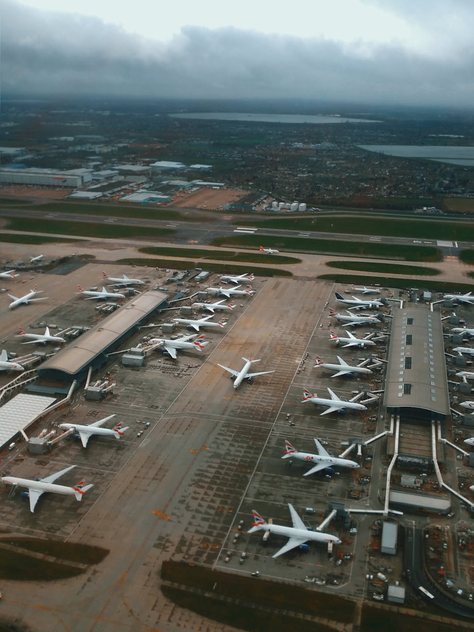 A sweeping aerial view of Heathrow Airport terminals in London, showcasing numerous aircraft and runways.