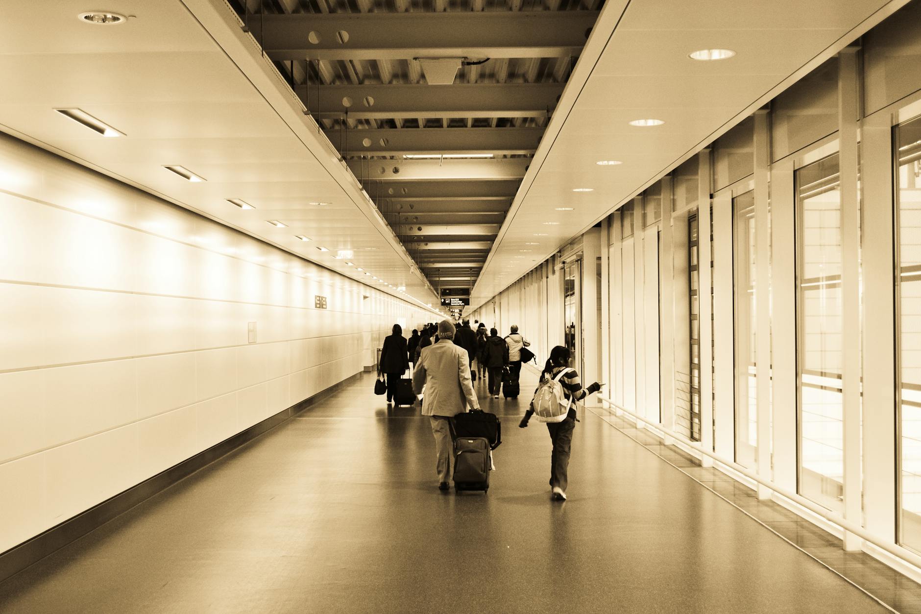 Travelers with luggage walking through a modern airport hallway with a vintage tone.