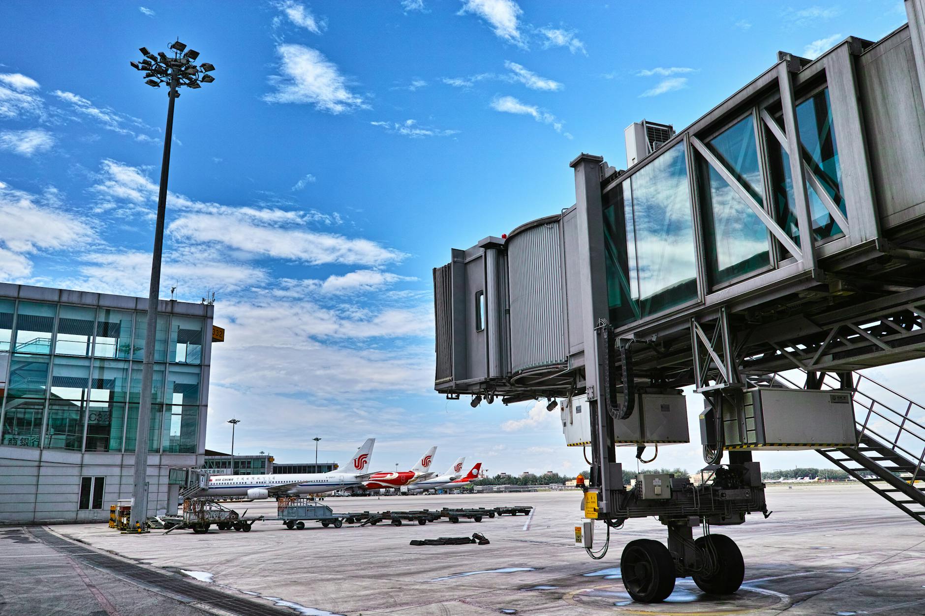 A jet bridge connects an aircraft at a busy airport on a clear day.