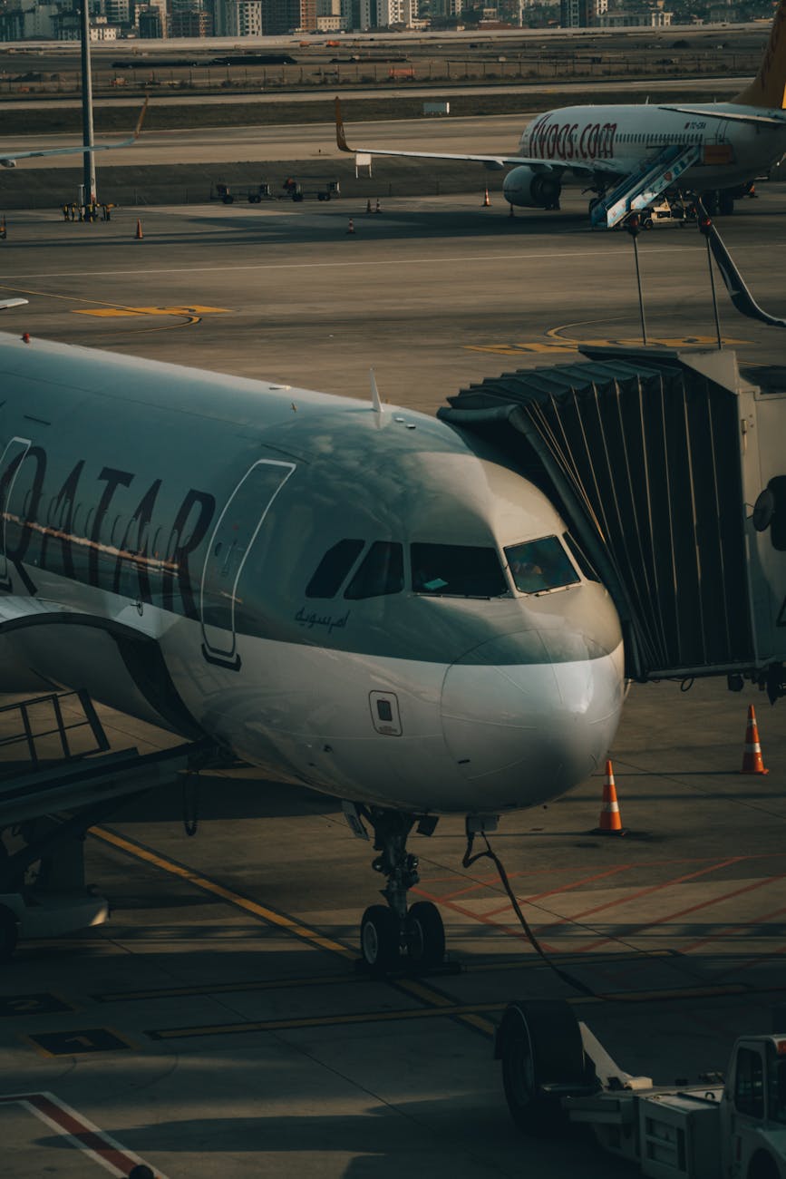 Aircraft docked at airport gate with passenger jet bridge during daytime.
