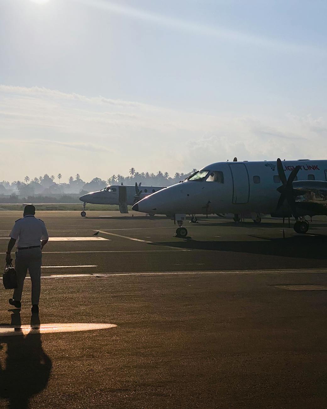 A pilot walks towards planes on a runway at sunrise in Arusha, Tanzania.