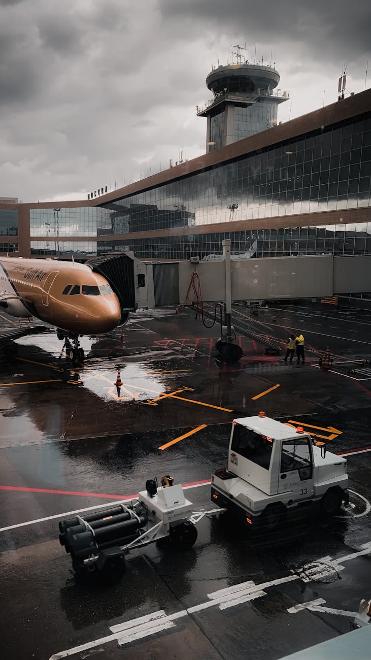 Airplane stationed at a modern airport terminal on a rainy day, capturing the busy atmosphere.