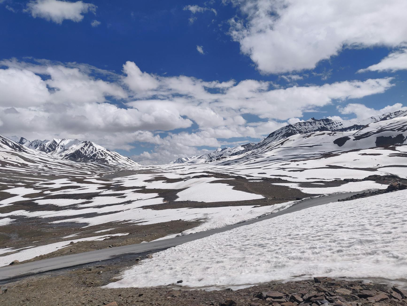 Serene winter view of Baralacha La Pass with snow-capped mountains under a blue sky.