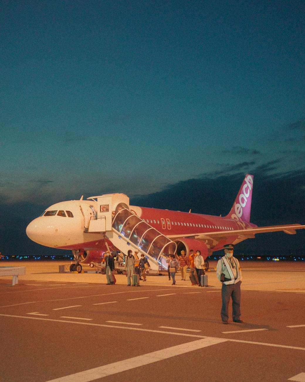 Passengers boarding an airliner during evening with a vibrant sky, showcasing travel and transportation.