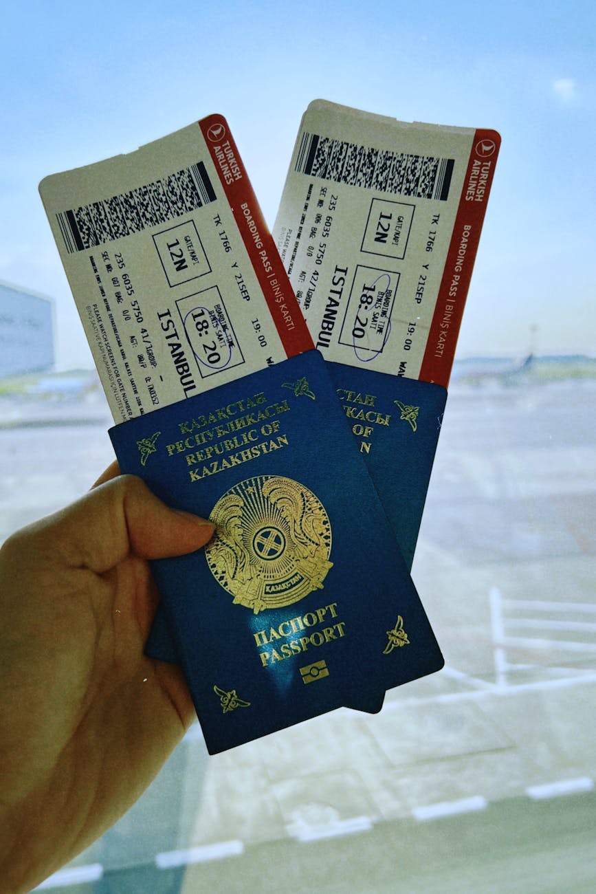 A Kazakhstan passport holds two airline tickets against an airport backdrop in Warsaw, Poland.