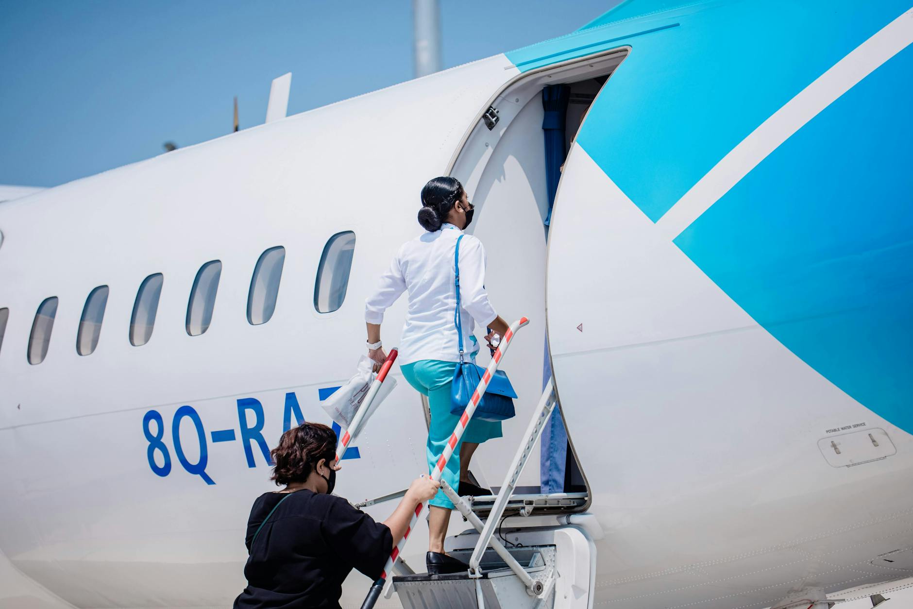 Passengers boarding an airplane under the clear Maldives sky, ready for travel.