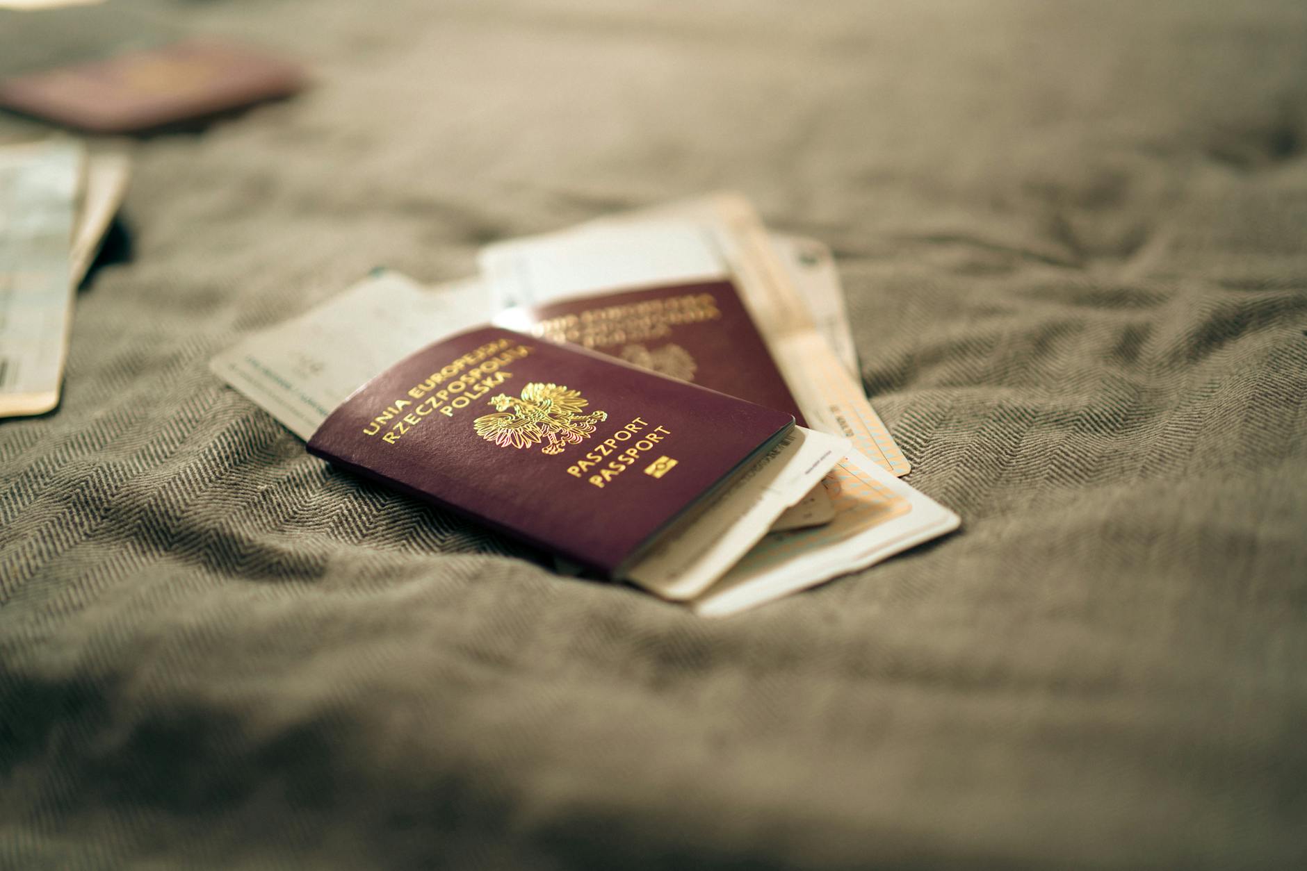 A close-up of a Polish passport and travel documents placed on a fabric surface, symbolizing travel and identity.