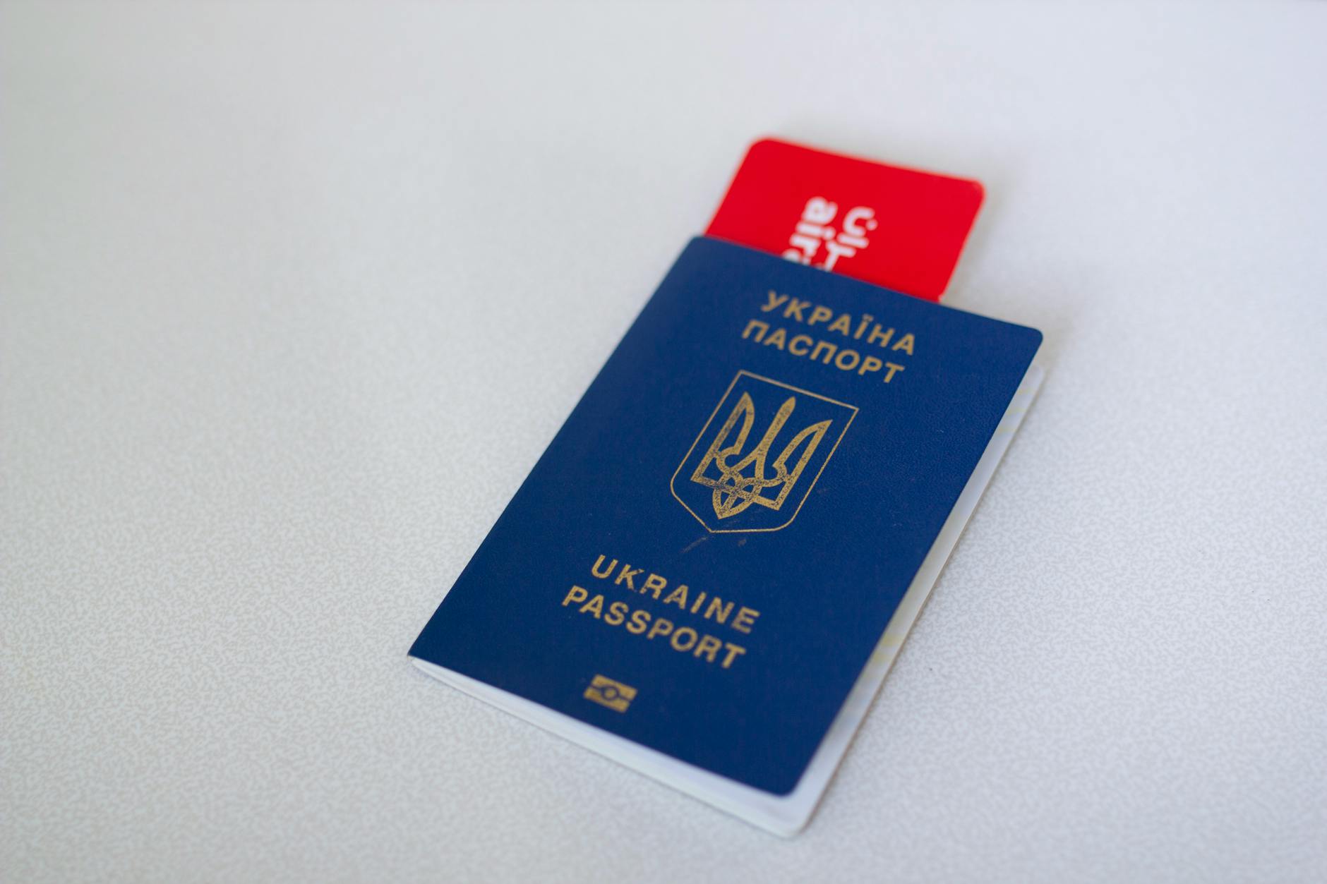 Blue Ukraine passport with airplane ticket on white surface. Travel concept.